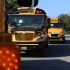 Line of yellow school buses parked outdoors during the day.